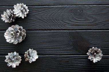Siyah ahşap masada gümüş kozalaklar, Noel arkaplanı. Metin için boşluk, kopyalama alanı. Üst görünüm. 