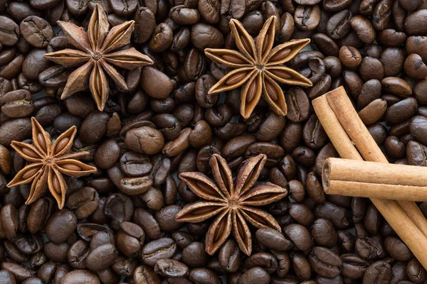 Anise stars and cinnamon sticks on coffee beans background. WInter Christmas concept.