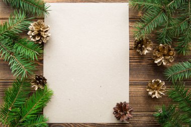 Kahverengi ahşap zemin üzerinde altın koniler ve köknar üç dal. Model yap, mesaj için boş yer var. Tebrik metni için boşluk. 