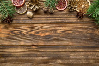 Noel tebrikleri arka planı. Portakallar, altın çam kozalakları, baharatlar, anason ve tarçın gibi kahverengi tahta arka planda köknar ağacı dalları. Boşluğu kopyala, metin için boşluk. 