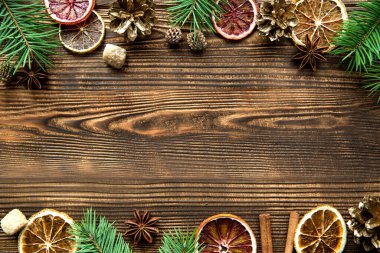 Noel tebrikleri arka planı. Arkadaş Sicilyalı portakallar, altın kozalaklar, baharatlar, anason ve tarçın gibi, kahverengi tahta arka planda köknar ağacı dalları. Boşluğu kopyala, metin için boş alan. 