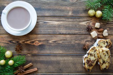 Kahverengi ahşap masada bir fincan sıcak kakao geleneksel Noel pastası, altın Noel süslemeleri ve köknar ağacı dalları. Mesaj için yer var. Boşluğu kopyala. 