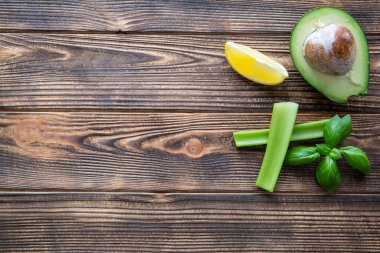 Avokado, kereviz sapı ve fesleğen yapraklarının yarısı kahverengi ahşap masada. Metin için boşluk, kopyala boşluk. 