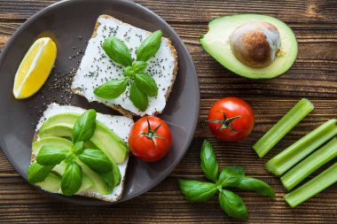 Kahverengi ahşap kırsal masada taze sebzeli ve kremalı peynirli avokado sandviçleri. Yakın plan. Üst görünüm. 