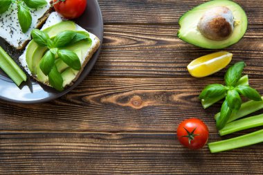 Kahverengi ahşap masada taze sebzeli bir tabak lezzetli avokado sandviçi. Metin için boşluk, kopyala boşluk. 