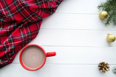 İskoç ekose, sütlü kırmızı bir fincan sıcak kakao, beyaz ahşap arka planda altın Noel süslemeleri. Boşluğu kopyala, metin için boşluk. 