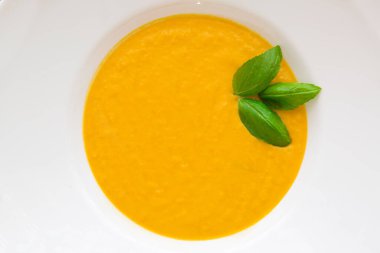 Lezzetli balkabağı kremalı çorba taze fesleğen yaprağı, baharat ve soğanla harmanlanmış. Üst görünüm, yakın çekim. 