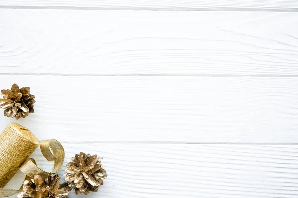 Golden pine cones and golden ribbons on white table, space for text, copy space. Christmas background, christmas table.