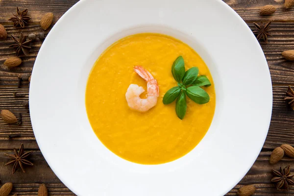 Tasty pumpkin cream soup with shrimps and basil leaves, blended with spice and carrots. Top view. — Stock Image Tasty Pumpkin Cream Soup Shrimps Basil Leaves Blended Spice Carrots Royalty Free Stock Images