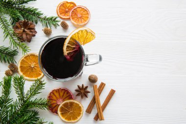 A cup of winter red mulled wine with citrus, cinnamon and anise spice on white table, top view. Space for text, top view.  clipart