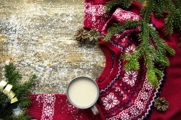 Kahverengi masada bir kupa sıcak kakao. Bir sürü kar ve geleneksel kırmızı kazak. Samimi sihirli Noel atmosferi. Metin için boşluk. 