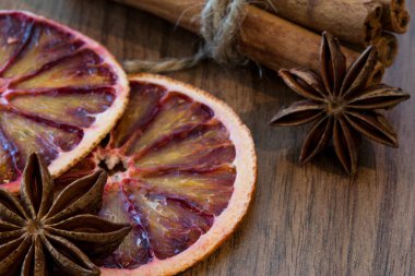 Kurutulmuş Sicilya portakalı ve kurutulmuş limon dilimi ile tarçın çubukları ve kahverengi ahşap arka planda anason yıldızları, yakın çekim. Makro. Noel atmosferi.
