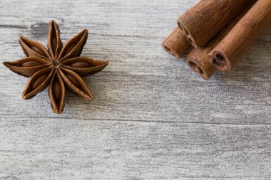 Anise yıldız baharatları ve tarçın gri ahşap arka planda yapışır, yakın plan, makro. 