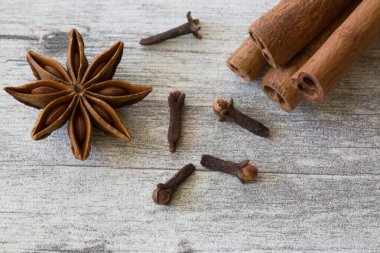 Anason yıldızları, karanfiller ve tarçın gri ahşap arka planda yapışır, yaklaşın, makro. 