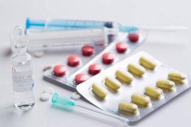 Beyaz arka planda haplar ve tabletler var. İğne için şırınga. Tedavi teması ve sağlık hizmetleri. 