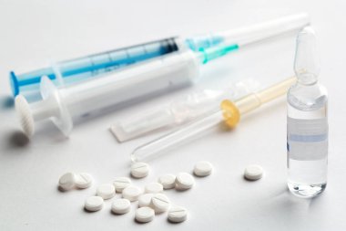 Beyaz arka planda şırınga ve beyaz pelteler. Ampul ve pipet, tıp konsepti.. 