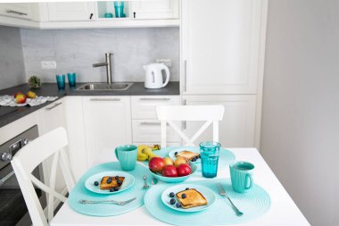 Modern tasarım mutfağında beyaz, gri ve turkuaz renklerde sağlıklı bir kahvaltı. Meyveli tost. 