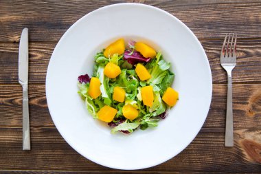 Kahverengi ahşap masada taze salata. Çatal bıçak servisi.. 