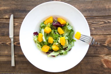 Kahverengi ahşap masada balkabağı salatası. Çatal bıçak servisi.. 