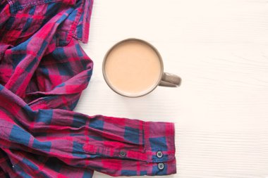 Bir fincan sıcak çikolata ve beyaz arka planda kırmızı tişört. Konforlu ev konsepti. Boşluk, kopyalama alanı. 