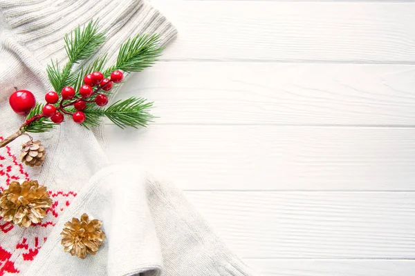 Beyaz ahşap arka planda noel süsü olan beyaz yün kazak. Noel kırmızı süslemesi. Selamlama alanı, kopyalama alanı. 