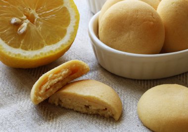 Taze limon ve çeşitli beyaz limonlu kurabiye bütün ve gri keten kumaş zemin üzerine dilimlenmiş