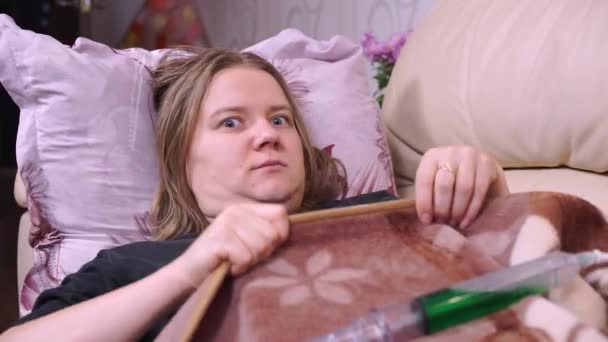 Больная девушка в домашнем карантине прячется под одеялом, видит шприц с вакциной — стоковое видео