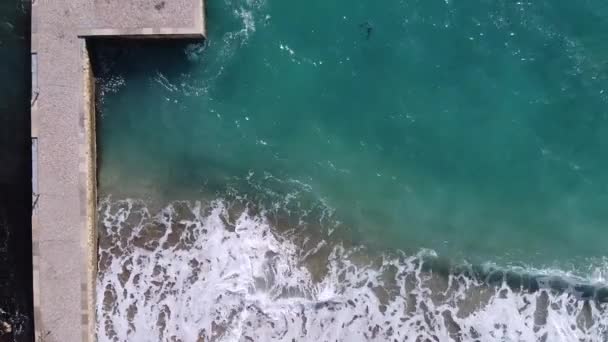 Emerald wave wast een strand zee met betonnen pier en grote rotsblokken, bovenaanzicht — Stockvideo