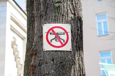 Prohibition sign that drones cannot be used in this area is hanging on tree in city. Modern technology for comfortable life. Violation of boundaries of private property. Permission to fly in midair. clipart