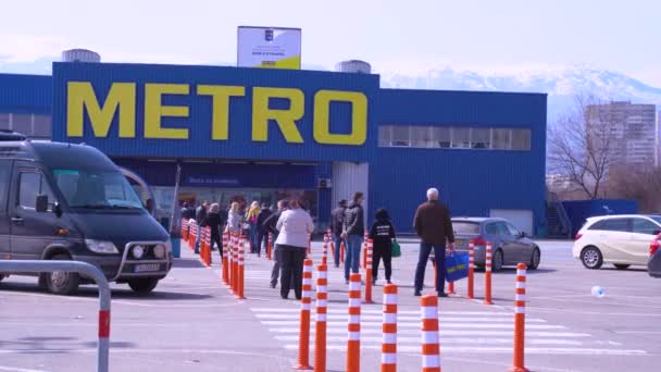 Sofia, Bulgarije 25 maart 2020: Mensen die in lange rij staan voor Metro Supermarket, houden een afstand vanwege coronavirus beschermende maatregelen. — Stockvideo