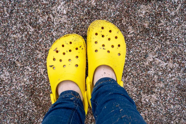 Nohy v džínách v jasně žluté gumě nebo plastových pantoflích. — Stock fotografie