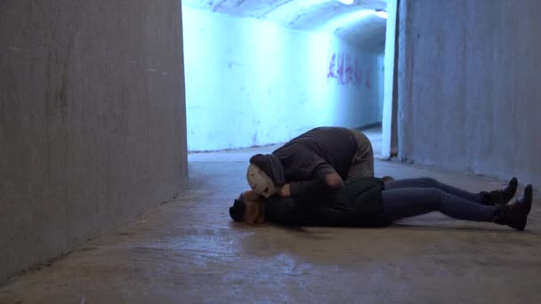 Earth after zombie apocalypse. Living dead attacked girl and eats her brain to satisfy hunger and spread the epidemic. Woman lying in convulsions on ground in corridor of underpass or shelter bunker. — Stock Video