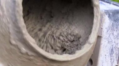 İnşaat alanındaki beton karıştırıcıda çimento çamuru ile kum ve çakılları karıştırma işlemi, yakın çekim. İnşaat ve inşaat mühendisliğinde kullanılan bağlayıcı madde üretim teknolojisi.