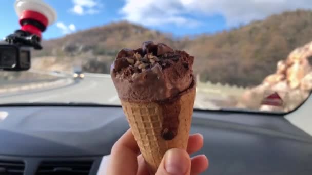 Cône de gaufre avec crème glacée au chocolat, tenue par quelqu'un dans une voiture en mouvement . — Video