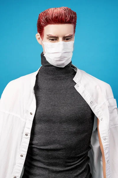 Mannequin man in medical coat and protective tissue respiratory mask on his face on blue background. Protection against threat of spread of virus. Reverse side of dangerous profession.