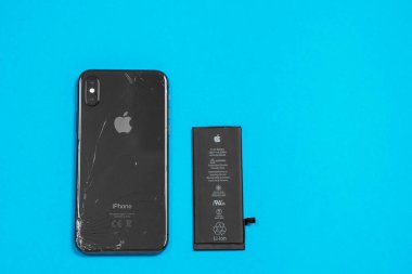 11 Nisan 2020, Rostov-on-Don, Rusya: Apple iPhone X 'ten Lityum iyon siyah pil ve mavi arka planda akıllı telefon. Akıllı telefonundaki eski hasarlı pili değiştiriyorsun.