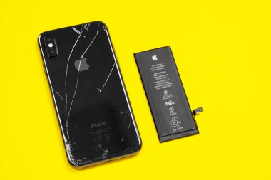 11 Nisan 2020, Rostov-on-Don, Rusya: Apple iPhone X 'ten Lityum iyon siyah pil ve sarı arka planda akıllı telefon. Akıllı telefonundaki eski hasarlı pili değiştiriyorsun.