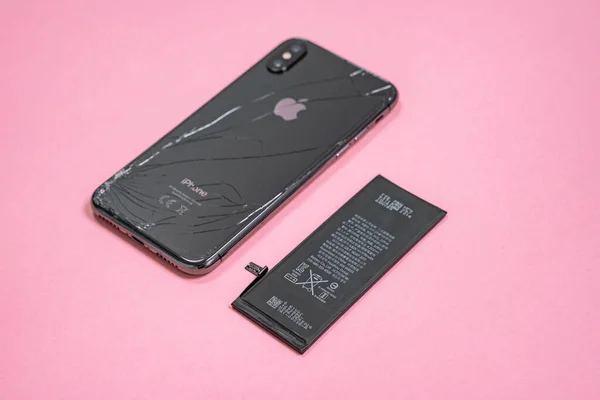 11 Nisan 2020, Rostov-on-Don, Rusya: Apple iPhone X 'ten lityum iyon siyah pil ve pembe arka planda akıllı telefon. Akıllı telefonundaki eski hasarlı pili değiştiriyorsun.