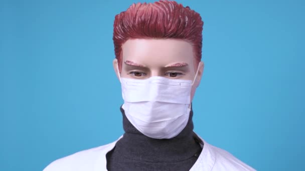 Mannequin homme en manteau médical et masque respiratoire de tissu protecteur sur son visage sur fond bleu, regarde autour. Protection contre la menace de propagation du virus. L'envers de la profession dangereuse — Video