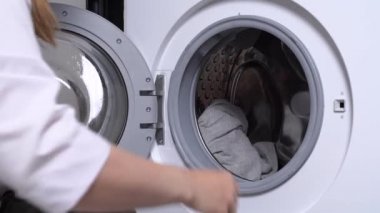 Çamaşırları çamaşır makinesine katlayan insan elleri.