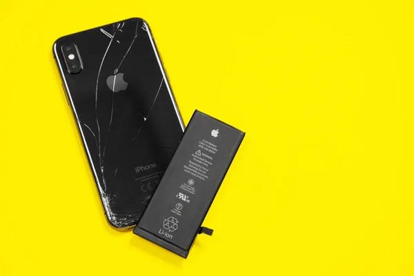 11 Nisan 2020, Rostov-on-Don, Rusya: Apple iPhone X 'ten Lityum iyon siyah pil ve sarı arka planda akıllı telefon. Akıllı telefonundaki eski hasarlı pili değiştiriyorsun.