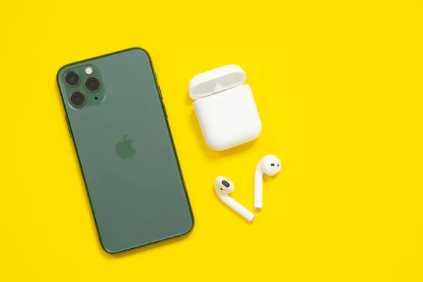 29 Nisan 2020, Rostov-on-Don, Rusya: Cep telefonu iPhone 11 Gece yarısı yeşil renkli Pro ve kablosuz kulaklıklar Sarı arka plan, üst görünüm, kopyalama alanı.