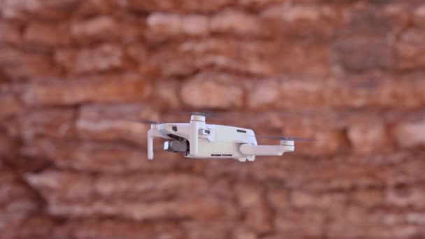 Malý dron létá na pozadí červených skalnatých hor — Stock video