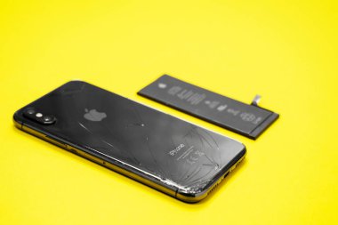 11 Nisan 2020, Rostov-on-Don, Rusya: Bozuk uzay gri renkli iPhone, cep telefonu ve taşınabilir cihazlar için lityum iyon pili sarı arkaplanda, kapat. Elektronik tamir reklamı