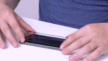Adam yeni bir akıllı telefonun ekranına düzgün bir şekilde kırılamaz koruyucu cam yerleştiriyor ve kapatıyor. Elektronik ve cihazlar için tamir hizmeti. Gadgets bakımı evde.