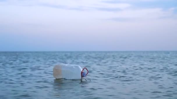 Vuoto sporco grande bottiglia di plastica alla deriva attraverso le onde al mare. Paesaggio con cielo e orizzonte blu pulito. Concetto di inquinamento ambientale . — Video Stock