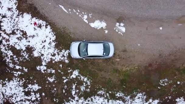 O carro de prata está estacionado no lado da estrada rural na estrada serpentina através do passo da montanha, floresta nevada rara no dia frio do inverno, câmera se afasta subindo verticalmente para cima, drone disparando de altura . — Vídeo de Stock