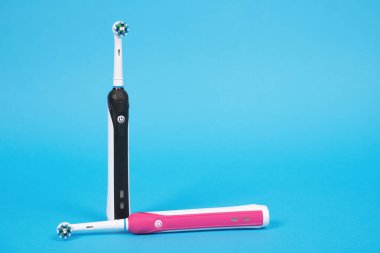 Pembe kızlar ve oğlanlar mavi arka planda yeni başlıklı siyah elektrikli diş fırçaları. Günlük sağlık ve ağız sağlığı için modern cihazların reklamı