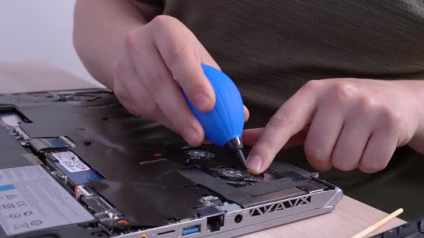 Man cleans dirt from laptop cooling fans system with silicone dust blower cleaner tool and soft brush covering the microcircuit with a protective film. Fixing gadgets at home or professional service. — Stock Video