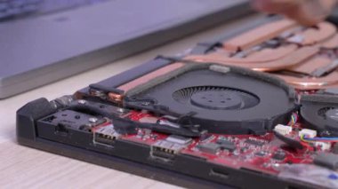 Adam, dizüstü bilgisayar soğutma sistemindeki kiri silikon toz temizleme aleti ve yumuşak fırçayla dikkatlice temizliyor. Elektronik ve aygıtlar için tamir hizmetinin reklamı.
